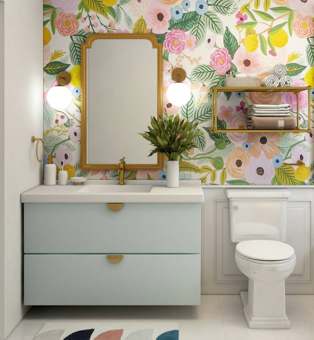 Well presented bathroom with vibrant wallpaper behind a mirror and floating vanity sink and pedestal toilet.